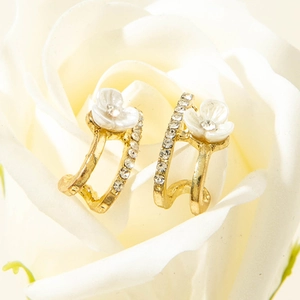 Elegant gold flower earrings with white petals and crystals on a fresh white rose