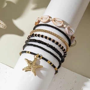Close-up of Bohemian layered beaded bracelet with golden starfish charm and natural shells