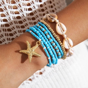 Macro detail of Bohemian beaded bracelet set featuring sea star charm and shells
