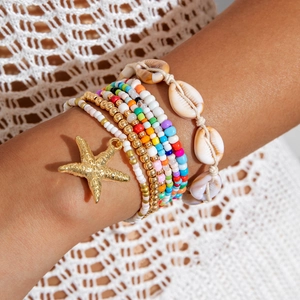 Detail of bohemian multilayer beads bracelet set with golden starfish and sea shell accents