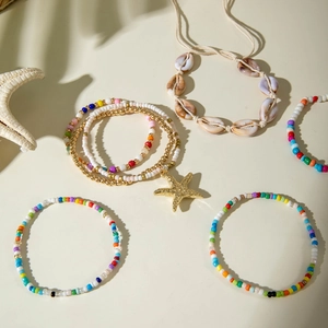 Close-up of bohemian beaded bracelet set featuring starfish charms and natural seashells