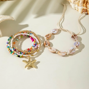 Close-up of bohemian starfish bead bracelet and shell cord wristlet in a beach scene