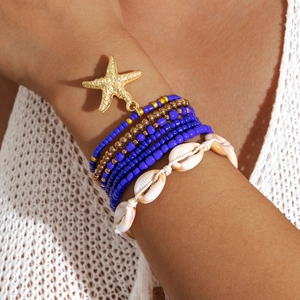 Detail of bohemian layered beach bracelets with starfish charms and shells on wrist