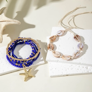 Detail of bohemian ocean beaded bracelet with gold starfish and shell on a stone pedestal