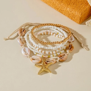 Detail of bohemian beach bracelet set with gold starfish charm and shell beads