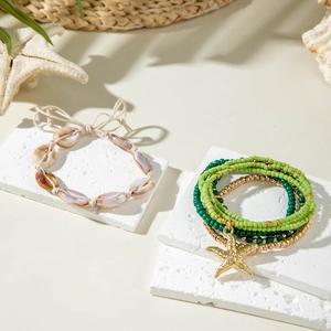 Detail of bohemian starfish charm bracelet and seashell beads on textured white background
