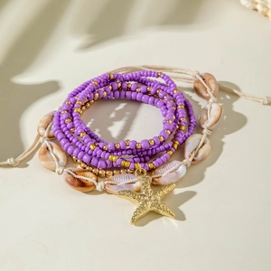 Detail of layered bohemian bracelets with purple beads, starfish charm, and shells