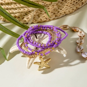 Bohemian purple and gold beaded bracelet set featuring a metallic starfish charm