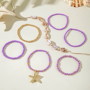 Detail of 7-piece bohemian purple beaded bracelet set with gold starfish and shell charms