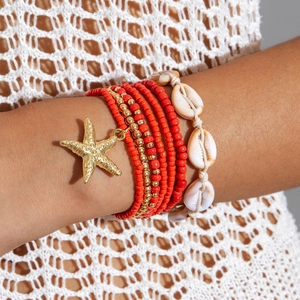 Detail of layered bohemian beach bracelet with red beads, gold starfish and natural shells
