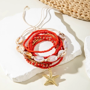 Detail of red beaded bohemian multilayer bracelet with gold starfish and sea shell accents
