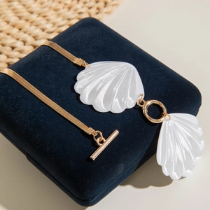 Golden snake chain with white acrylic shell pendants on a navy blue velvet box