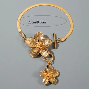 Detailed close-up of golden floral charm on a snake chain with a 23cm length measurement