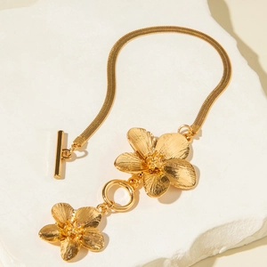 Close-up of gold flower pendants with brushed texture and T-bar clasp on snake chain