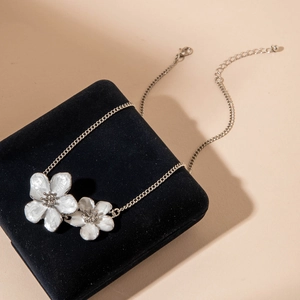 Detail of silver chain necklace featuring dual white flower pendants with crystal centers