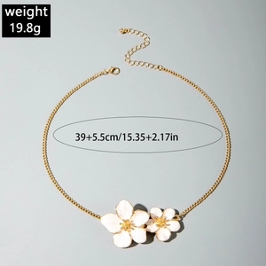 Macro view of gold flower necklace with white enamel petals and adjustable chain measurements