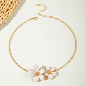 Detailed shot of golden necklace with white enamel floral pendants and adjustable clasp