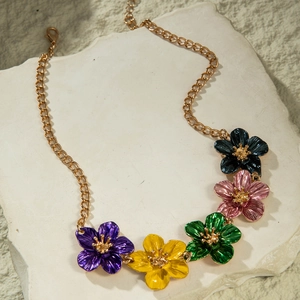 Close-up of five colorful enamel flower charms on a gold-plated necklace chain