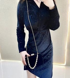 Detail of a black sequin evening dress paired with a luxury gold chain clutch bag