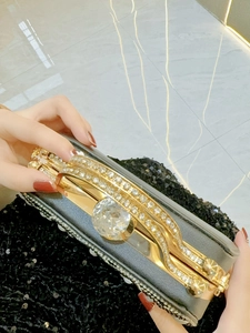 Detailed macro view of luxury clutch bag featuring gold crystal rhinestones and handle