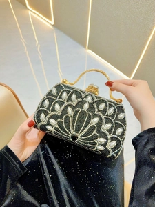 Detail of luxury evening handbag with black rhinestones, pearls and gold circular handle