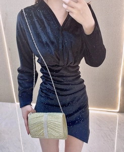 Close-up of a gold clutch bag with vertical crystal rhinestones and textured pleats