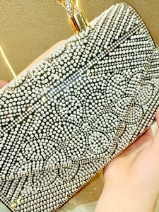 Close-up of luxury white pearls and rhinestones on the golden evening clutch bag