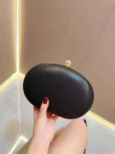 Détail d'une pochette de soirée noire avec cadre doré et fermoir boule en strass brillant