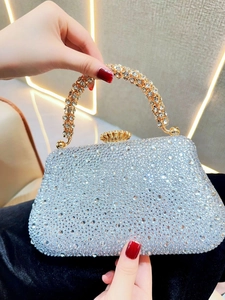 Détail d'une pochette argentée en strass avec poignée en cristal et cadre doré chic