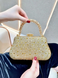 Détail d'une pochette de soirée dorée ornée de strass avec une poignée en cristal chic