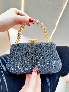 Détail d'une pochette de soirée noire avec strass et poignée en cristal doré
