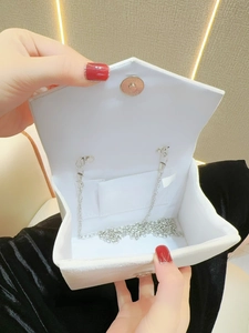 White velvet envelope evening bag with silver chain strap shown in an open hand-held view