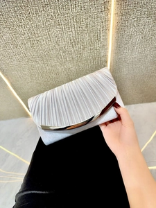 Detail of silver pleated evening clutch bag with metallic clasp held by a woman