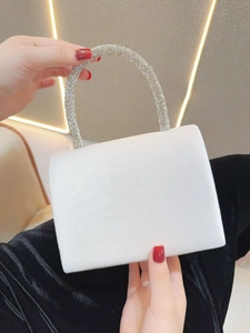 Close-up of white satin evening clutch with luxury rhinestone-encrusted handle detail