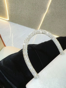 Detail of a luxury black velvet evening bag featuring a crystal-encrusted round handle