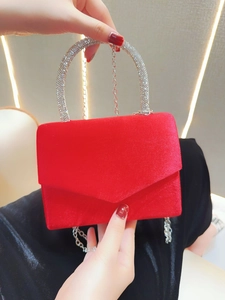 Detailed view of red velvet evening bag featuring a crystal-encrusted semicircular handle