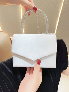 Close-up of elegant white velvet evening clutch with rhinestone circular handle and chain