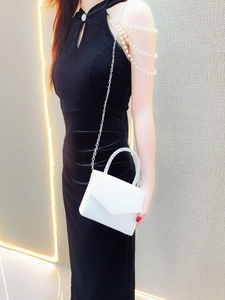 Model wearing a white velvet evening bag with rhinestone handle and silver chain strap