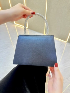 Detail of a black satin evening bag with a luxury rhinestone encrusted handle