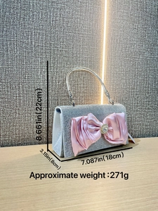 Silver rhinestone evening bag with a large pink satin bow and pearl accent on a desk