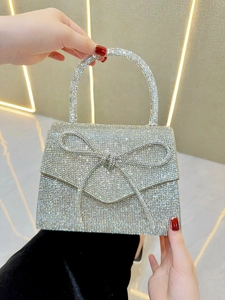Close-up of sparkling rhinestone bow detail on a silver formal evening clutch bag