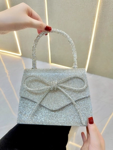 Close-up of sparkling rhinestone bow detail and silver crystal pavé on a luxury evening bag