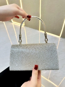 Detail of silver rhinestone evening bag featuring a crystal bow and metallic knot handle