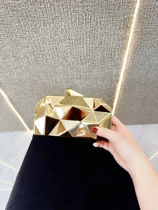 Detailed close-up of a golden geometric evening clutch bag with metal lock clasp