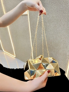 Close-up of golden geometric evening clutch bag with faceted mirror surface and chain