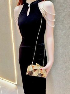 Close-up of a gold geometric clutch bag featuring mirror-finish facets and a slim chain