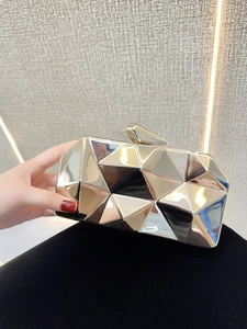 Close-up of a light gold geometric faceted acrylic evening clutch with metal clasp