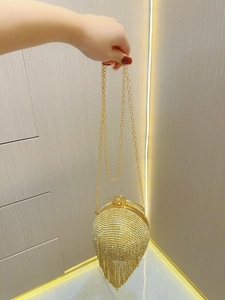 Detail of gold rhinestone evening clutch with sparkling crystal tassels and chain strap