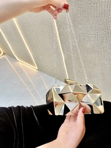 Close-up of a silver geometric faceted acrylic clutch bag with a detachable metal chain strap