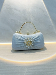 Close-up of silver-blue glitter evening clutch with rhinestone floral detail and gold handle